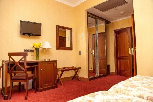a hotel room with a desk with a television and a bed at Reikartz Kamianets-Podilskyi in Kamianets-Podilskyi