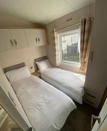 two beds in a small room with a window at Westfield Lodge Retreat-Sleeps 6-Pet Friendly in Carnforth