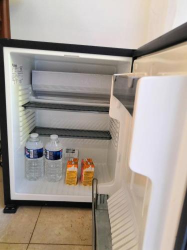 - un réfrigérateur ouvert avec des bouteilles d'eau et du lait dans l'établissement Unique havre de paix, à Nice