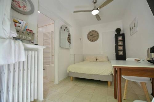 - une chambre avec un lit, une table et une horloge dans l'établissement Unique havre de paix, à Nice