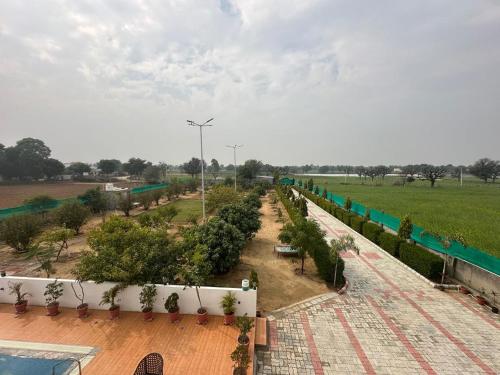 a row of trees in a garden next to a field at Farm retreat in Jaipur