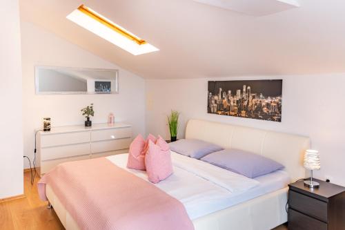 a bedroom with a white bed with pink and blue pillows at Apartman Petra s pogledom na more in Banjol