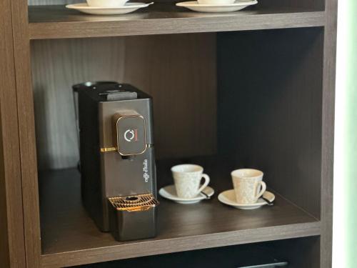 a coffee machine with two cups on a shelf at Sunset Guest House in Reggio Calabria