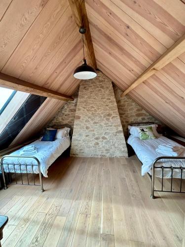 deux lits dans une chambre avec plafonds en bois dans l'établissement Le Sémaphore de Lervily, à Audierne