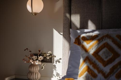 a bed with a pillow and a vase on a table at 1864 Apartments in Zakynthos
