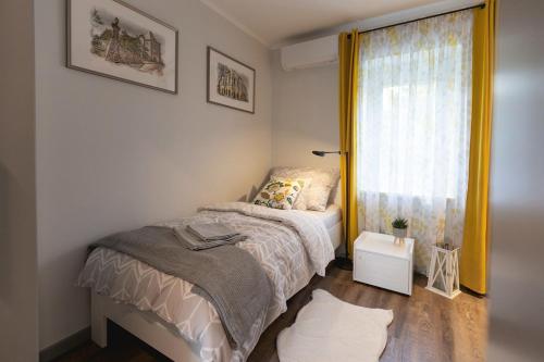 a small bedroom with a bed and a window at Hóvirág Apartman in Hódmezővásárhely