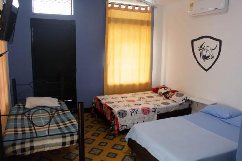 a room with two beds and a window and a door at Hotel El Barcino in Neiva