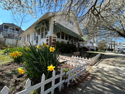 a white fence in front of a house with yellow flowers at Cottage near beach and boards! in Ocean City