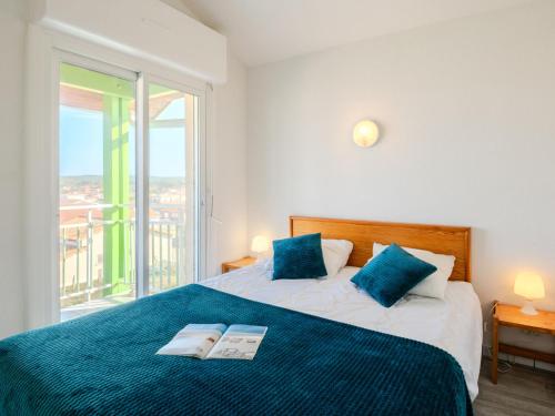 une chambre avec un lit avec des oreillers bleus et une fenêtre dans l'établissement Apartment les Goelands by Interhome, à Mimizan-Plage
