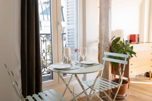 une table et des chaises dans une pièce avec une fenêtre dans l'établissement Appartement Candie - Welkeys, à Paris