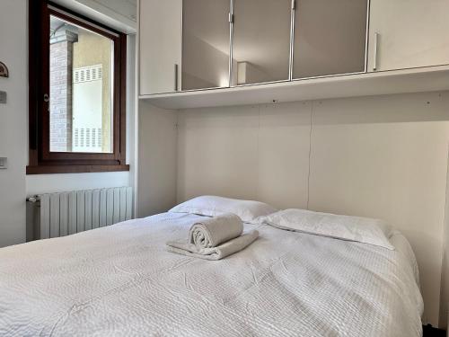 a white bed with a towel on top of it at Monolocale con giardino privato e cucina completa in Bergamo