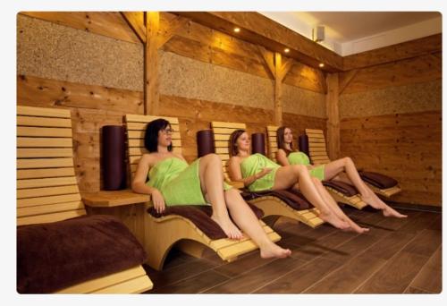 three women in green dresses sitting in a sauna at Ferienwohnung Familie Kitzke in Teisnach