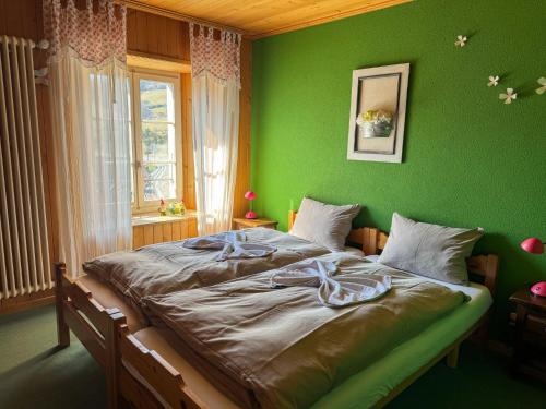 una camera verde con un grande letto di fronte a una finestra di Auberge de l'Ange ad Albeuve