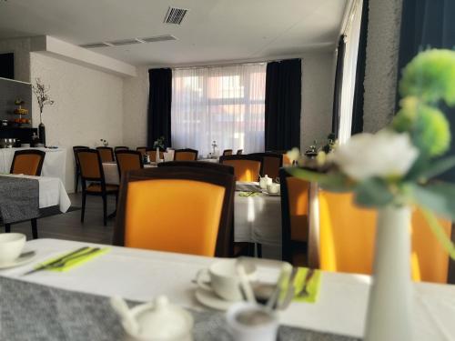 City Hotel Neuwied في نيوفيد: غرفة طعام مع طاولات بيضاء وكراسي صفراء