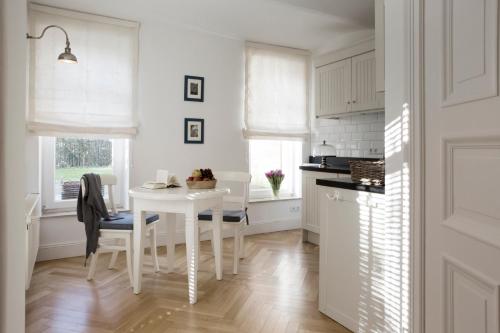 a white kitchen with a white table and chairs at von Deska Townhouses - White House in Hamburg