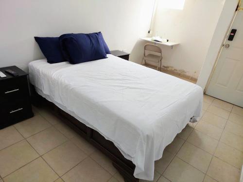 Un dormitorio con una cama blanca con almohadas azules. en Cómodo departamento 2 cerca del centro de gobierno , CAS, Consulado , CRIT, en Hermosillo