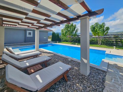 a swimming pool with a pergola next to a swimming pool at Holiday Home Maja by Interhome in Donji Proložac