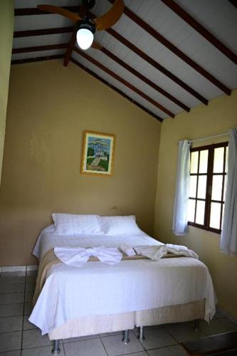 a bedroom with a white bed with a ceiling at Tangaras da Serra in Macaé