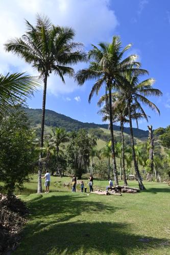 a group of people walking in a park with palm trees at Tangaras da Serra in Macaé