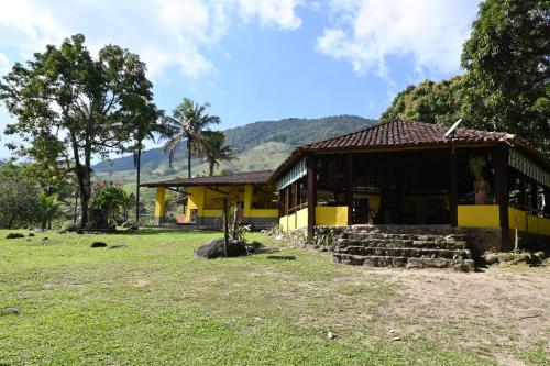 a yellow building with a porch and a grass field at Tangaras da Serra in Macaé
