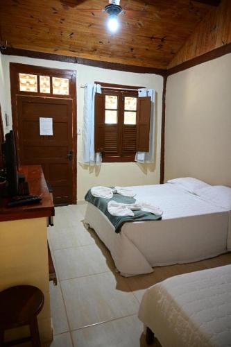 a bedroom with a bed and a desk and window at Tangaras da Serra in Macaé