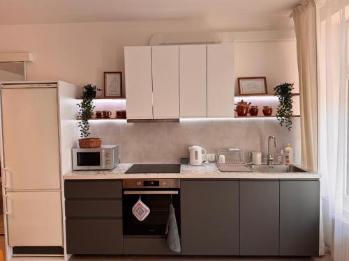 a kitchen with white cabinets and a sink and a microwave at Mieszkanie bez barier, przytulność na każdym kroku in Myślenice