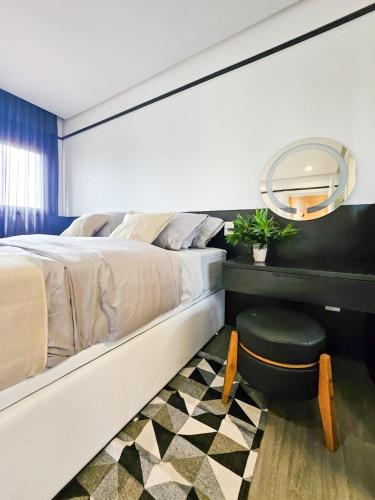 a bedroom with a bed with a stool and a mirror at GO Rio Branco by LikeHome in Porto Alegre