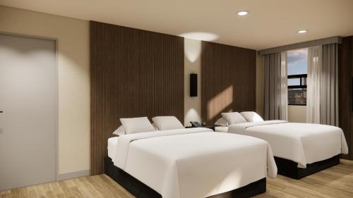 two beds in a hotel room with white sheets at Kins Hotel in Los Angeles