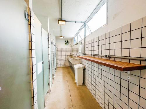 a bathroom with a toilet and a sink and a window at Laika Hostel in Camburi