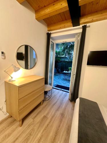 a bedroom with a dresser and a mirror and a door at In CITY CENTER with PATIO in Como