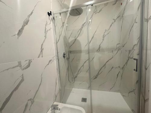 a white bathroom with a shower and a sink at Sunset Guest House in Reggio Calabria