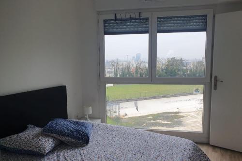 une chambre avec un lit et une grande fenêtre dans l'établissement Charming T3 with parking near Paris, à Villejuif