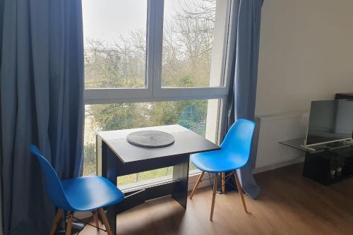 une table et deux chaises bleues devant une fenêtre dans l'établissement Charming T3 with parking near Paris, à Villejuif