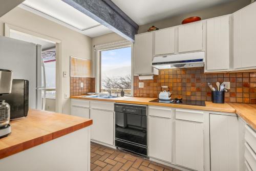a kitchen with white cabinets and a large window at Oak Ridge Retreat by Snowmass Vacations in Snowmass Village
