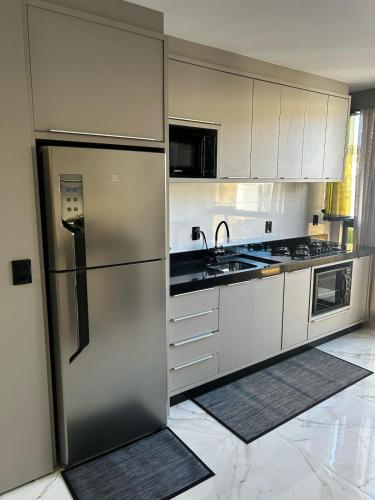 a kitchen with white cabinets and a stainless steel refrigerator at Apartamento Piratuba Alegria, 104 in Piratuba