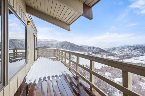 a bench on a balcony with a view of snow covered mountains at Oak Ridge Retreat by Snowmass Vacations in Snowmass Village