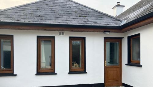 a white house with wooden doors and windows at Iniscealtra Mini Bedsit Studio in Mountshannon