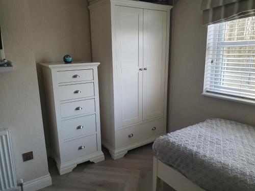 a bedroom with a white cabinet and a bed at Routh 2-Bed Luxury Lodge Hot Tub & Lake View in Routh