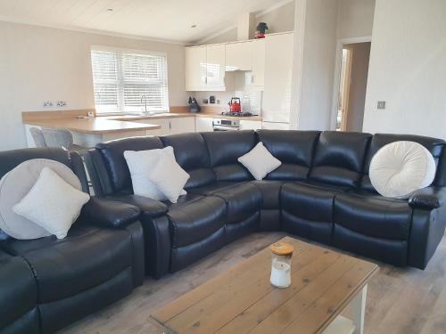 a black leather couch in a living room with a table at Routh 2-Bed Luxury Lodge Hot Tub & Lake View in Routh