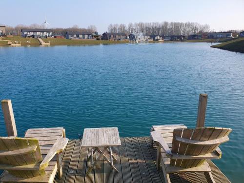 two chairs and a table on a dock on a lake at Routh 2-Bed Luxury Lodge Hot Tub & Lake View in Routh