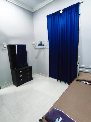 a bedroom with a blue curtain and a tv at Homestay Hillview in Selising