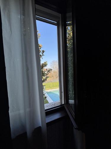 a window with a white curtain and a view of a pool at La Celeste Galeria in Mantova