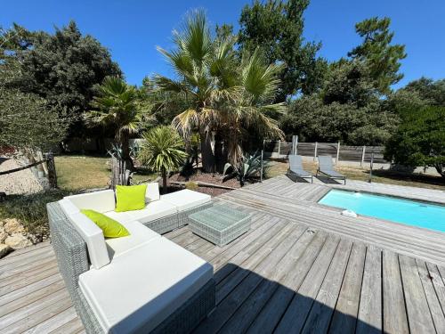 - un canapé blanc assis sur une terrasse en bois à côté d'une piscine dans l'établissement Dépendance avec piscine et spa partagés - plage 130 m, à Soulac-sur-Mer