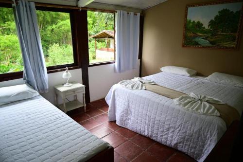 a bedroom with two beds and a window at Tangaras da Serra in Macaé