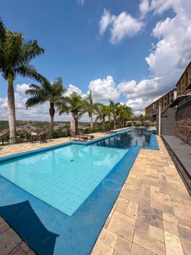 a large swimming pool with palm trees in a resort at Condomínio Alto da Serra Villas in Bananeiras