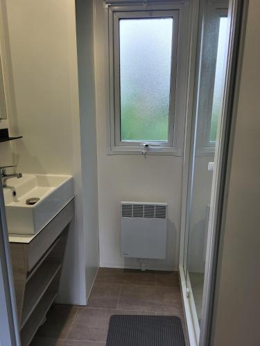 a bathroom with a sink and a window at Mobile home 6P XL Climatisation TV WIFI parcelle XXL au calme in Ivry-la-Bataille
