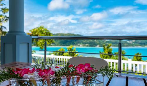 a table with flowers on a balcony with a view of the ocean at CASA GEM in Victoria