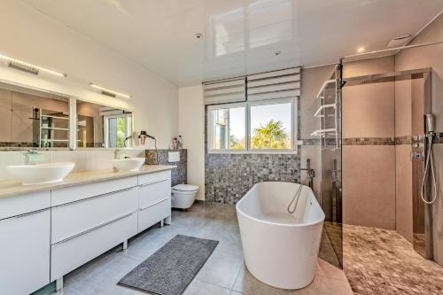 une salle de bain avec deux lavabos, une baignoire et une douche dans l'établissement La Villa Chantalain, à Kerlouan