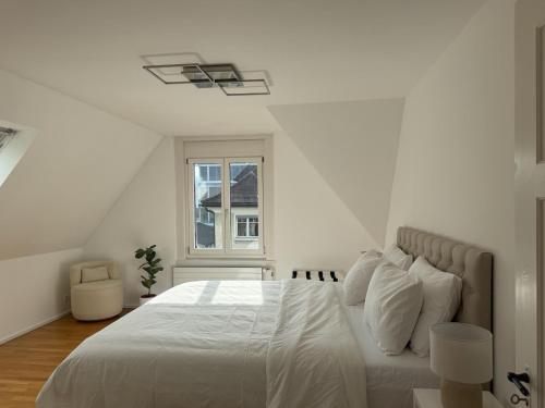 a white bedroom with a large bed with a window at Haus Zum Park - The apartment in Baden