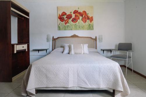 a bedroom with a bed and a painting of flowers at El Descanso in San Antonio de Areco